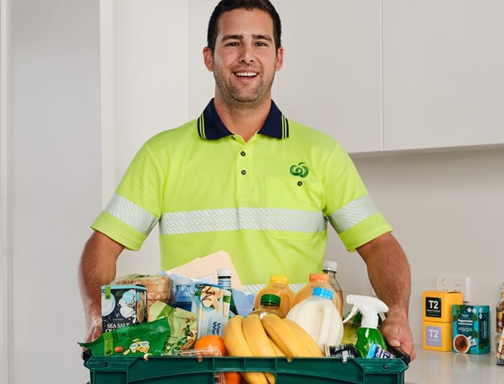 Woolworths at Work delivery driver holding a crate of products