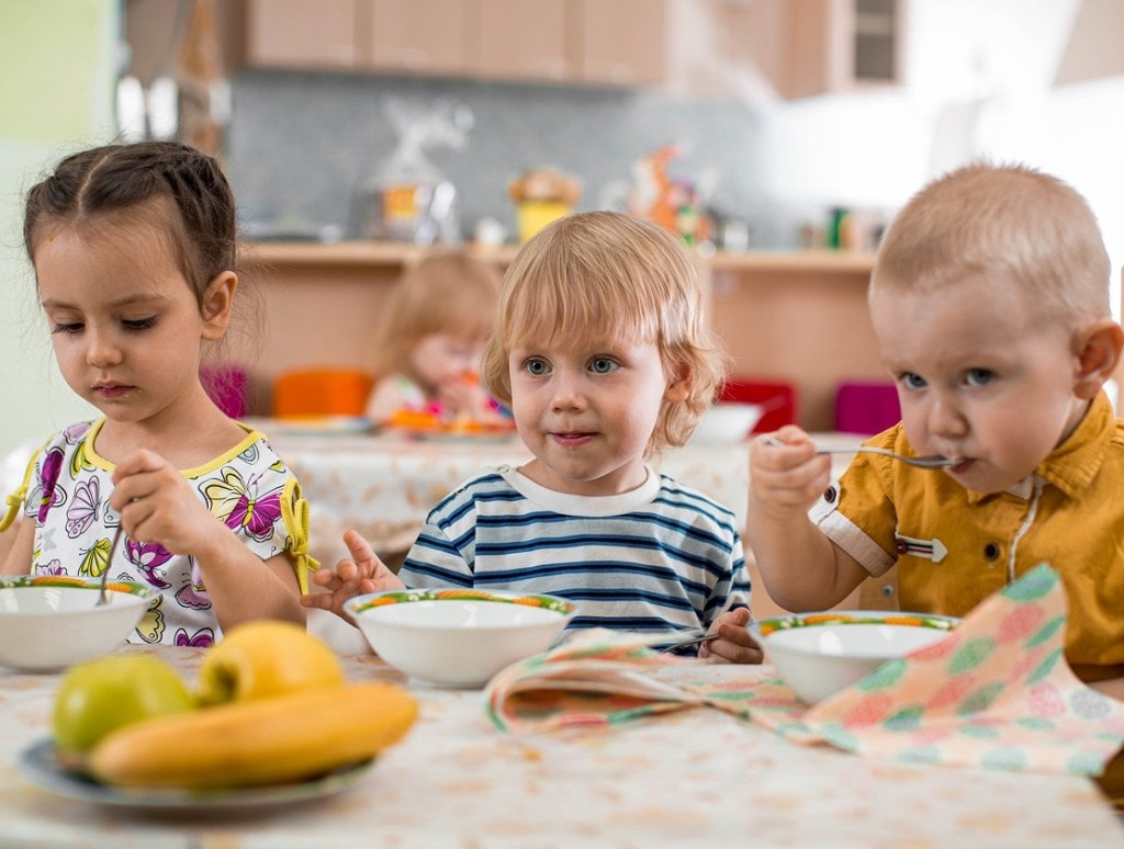 children at daycare eating breakfast at a table