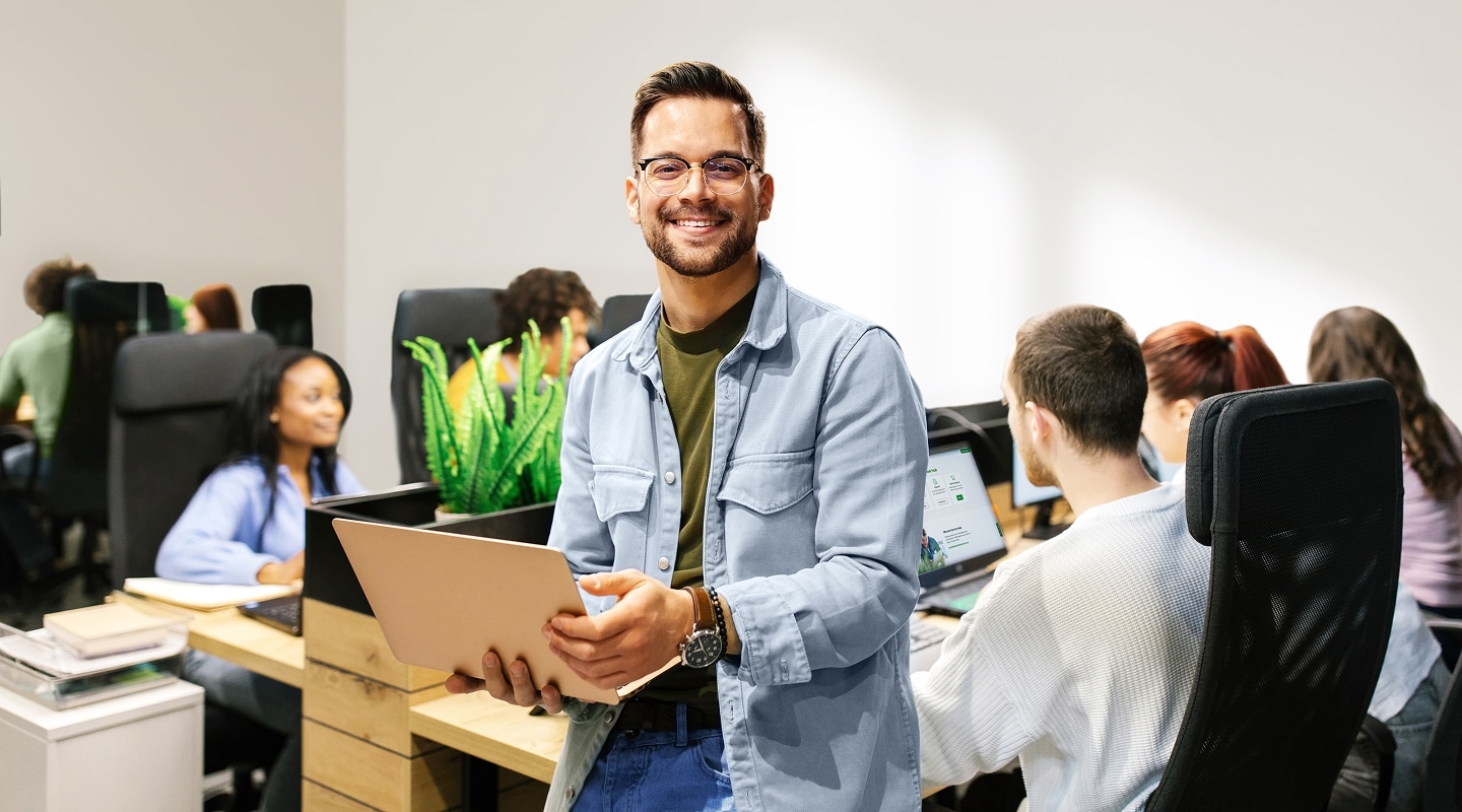 Office worker sitting on desk with laptop