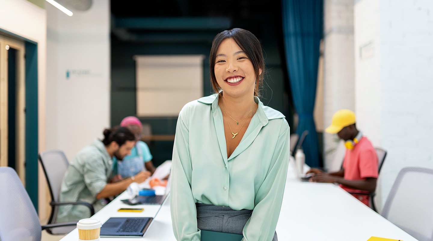 Office worker sitting on desk with laptop